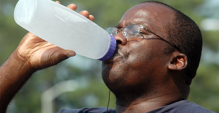 Man Drinks From Water Bottle For Relief From Heat