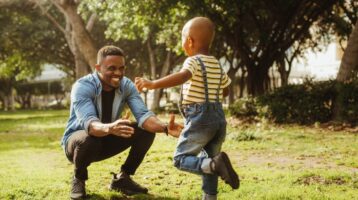 Child and father play in a park.