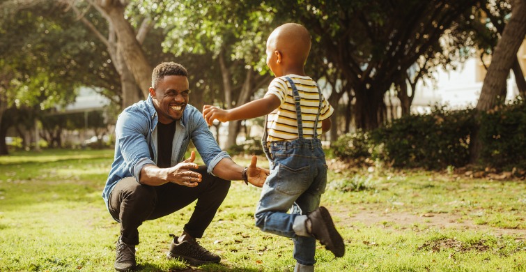 Child and father play in a park.