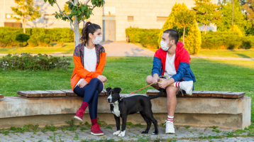Couple with a dog wearing masks.