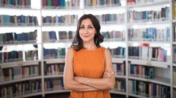 Female Librarian surrounded by library bookshelves
