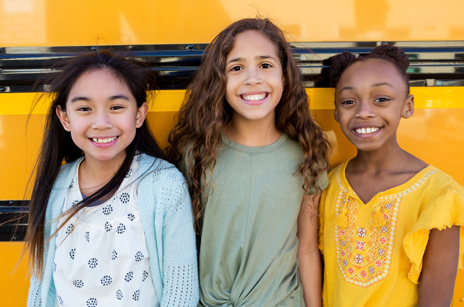 three girls in front of school bus