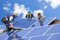 three men install solar panels
